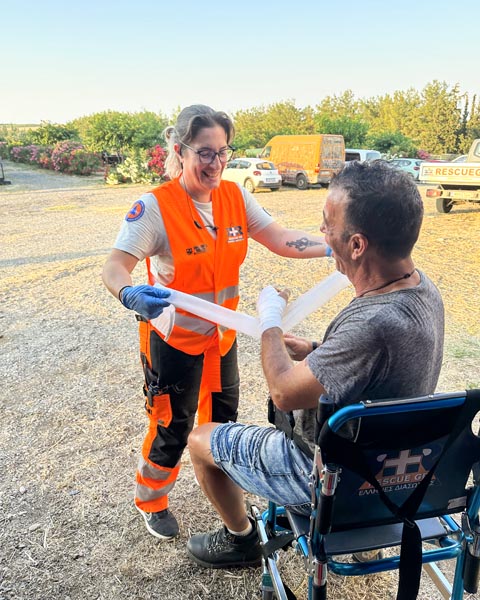 Εθελόντρια διασώστρια παρέχει πρώτες βοήθειες σε πολίτη.